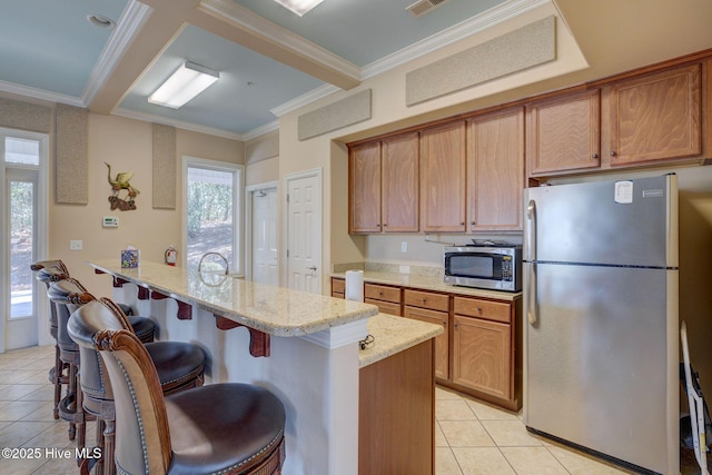 kitchen featuring a breakfast bar, light tile patterned floors, ornamental molding, stainless steel appliances, and light stone countertops