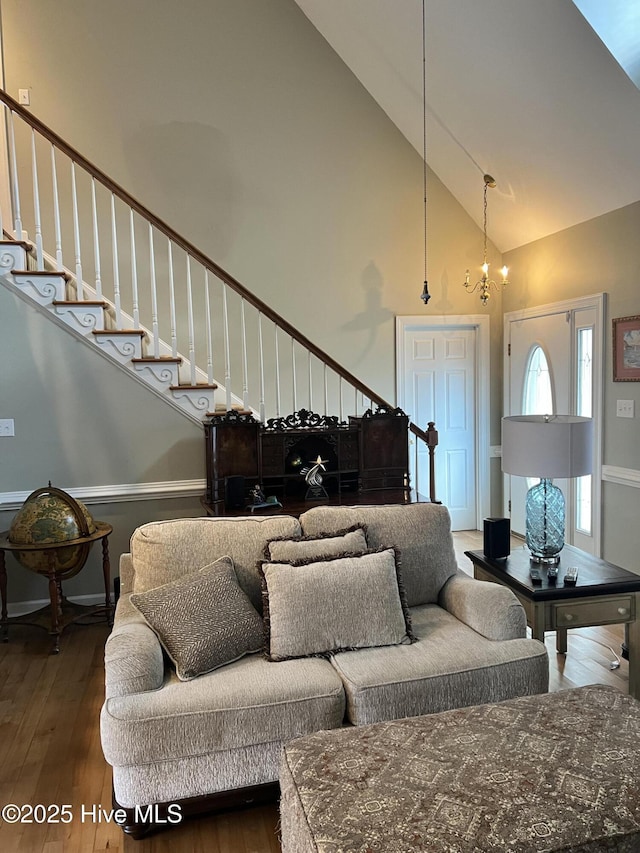 living room featuring dark hardwood / wood-style flooring, high vaulted ceiling, and a notable chandelier