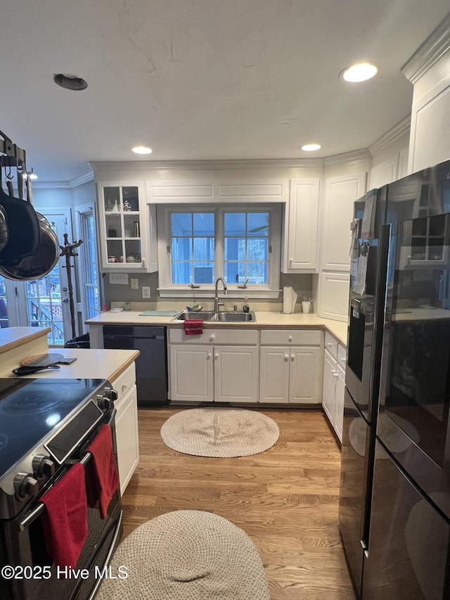 kitchen with white cabinets, sink, light hardwood / wood-style flooring, and black appliances