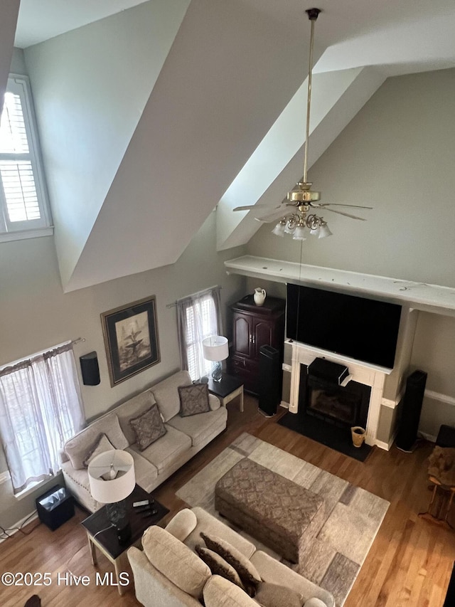 living room featuring hardwood / wood-style floors, lofted ceiling with skylight, and ceiling fan