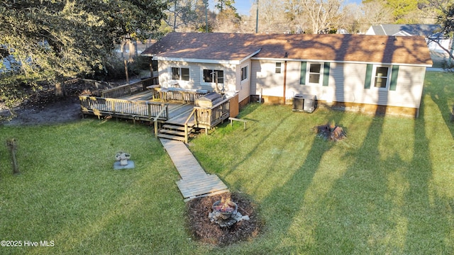 back of property featuring roof with shingles, a yard, and a wooden deck