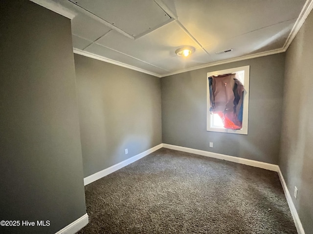 empty room with attic access, baseboards, visible vents, ornamental molding, and dark colored carpet