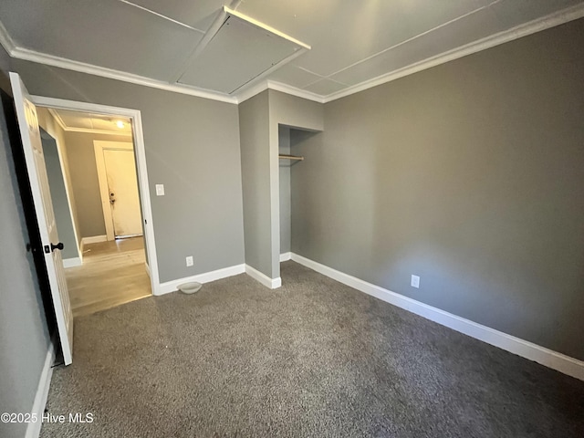 unfurnished bedroom with attic access, ornamental molding, baseboards, and carpet flooring