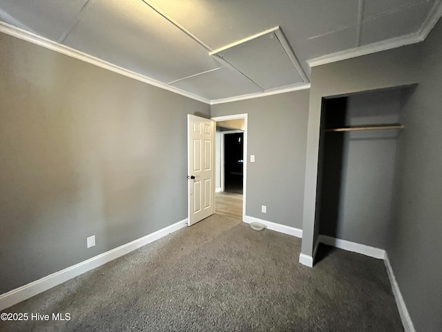 unfurnished bedroom featuring carpet flooring, baseboards, ornamental molding, a closet, and attic access