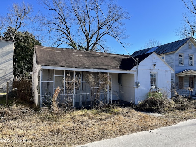 view of front of property with a sunroom and roof with shingles