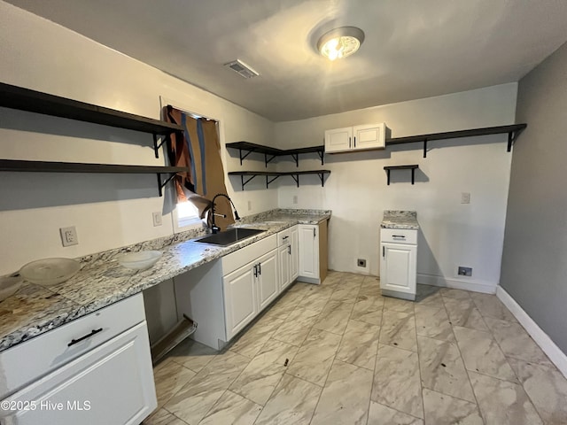 kitchen with a sink, visible vents, white cabinets, marble finish floor, and open shelves