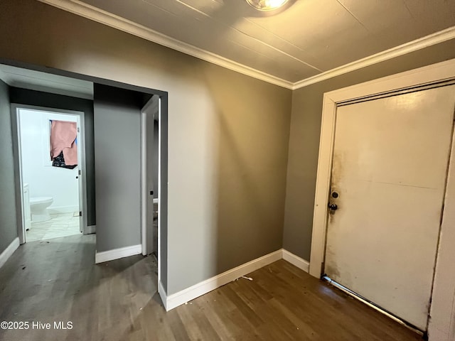 interior space featuring baseboards, crown molding, and wood finished floors