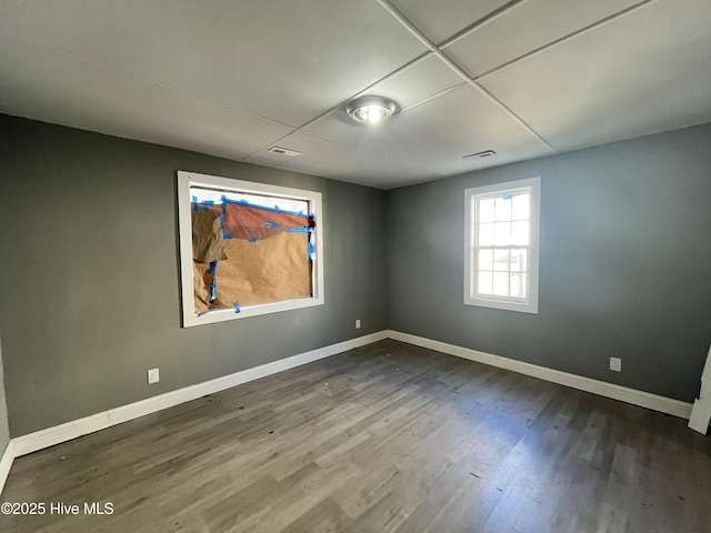 empty room featuring dark wood-style floors, visible vents, and baseboards