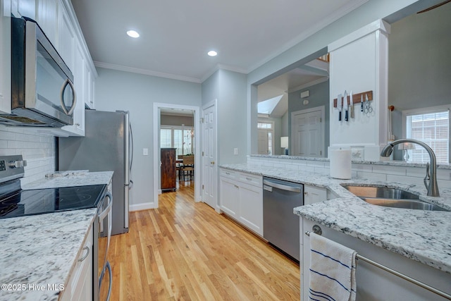 kitchen with light stone countertops, appliances with stainless steel finishes, backsplash, sink, and white cabinets