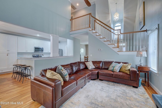 living room with a healthy amount of sunlight, a high ceiling, and light wood-type flooring