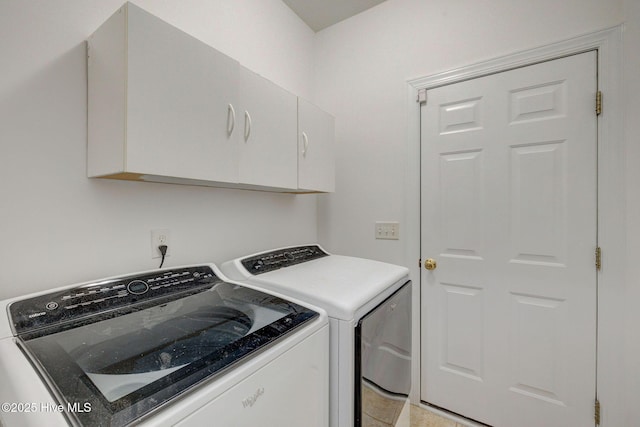 washroom with washing machine and dryer, light tile patterned floors, and cabinets