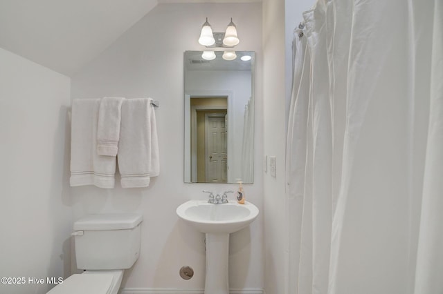 bathroom featuring sink, vaulted ceiling, and toilet