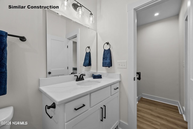 bathroom featuring toilet, vanity, and hardwood / wood-style flooring