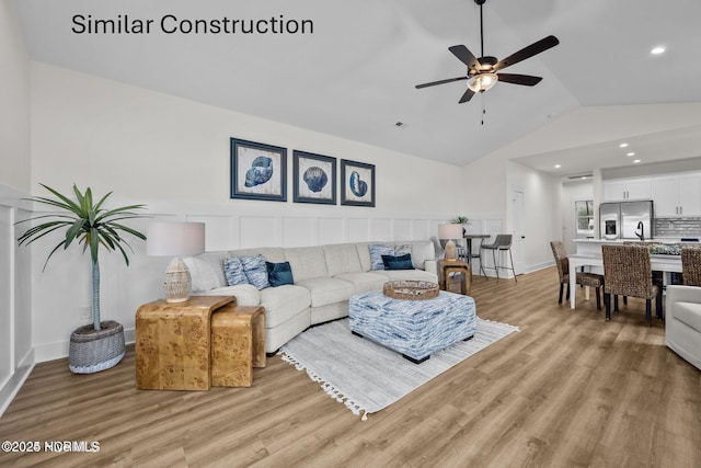 living room featuring light wood-type flooring, ceiling fan, lofted ceiling, and sink