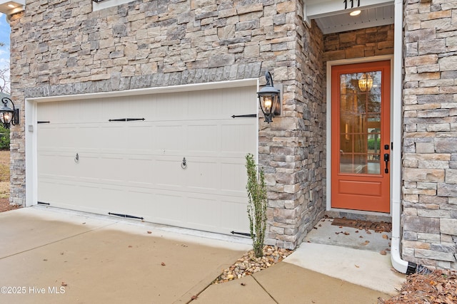 entrance to property with a garage, stone siding, and roof with shingles