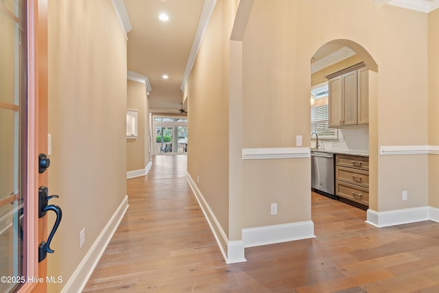 hall featuring light hardwood / wood-style flooring, crown molding, and sink