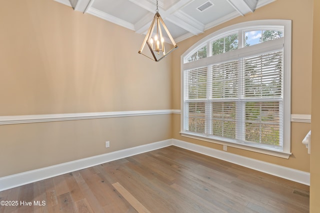 unfurnished dining area featuring ornamental molding, coffered ceiling, hardwood / wood-style flooring, an inviting chandelier, and beamed ceiling