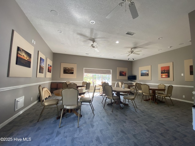 dining space featuring ceiling fan, dark carpet, and a textured ceiling