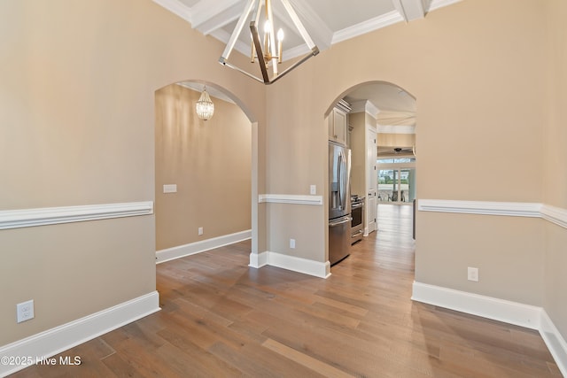 spare room featuring crown molding, hardwood / wood-style floors, and a chandelier