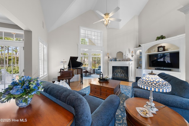 living room with a wealth of natural light, ceiling fan, built in features, and a premium fireplace