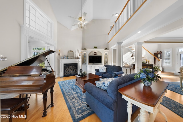 living room featuring ornate columns, ceiling fan, light hardwood / wood-style floors, and a high ceiling