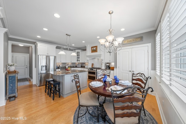 dining room with a chandelier, light hardwood / wood-style floors, and crown molding