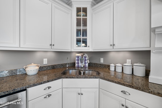 kitchen with white cabinets, dark stone countertops, stainless steel dishwasher, and sink