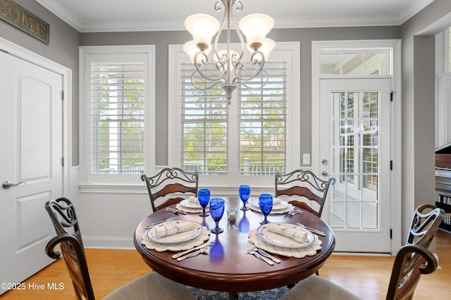 dining space featuring light hardwood / wood-style flooring, a chandelier, and ornamental molding