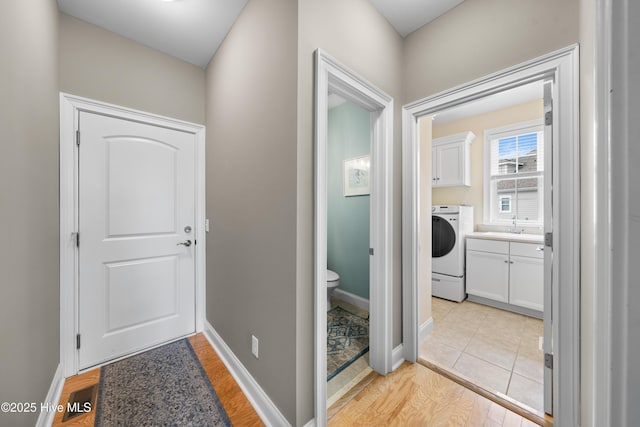 hall with sink, light hardwood / wood-style floors, and washer / dryer