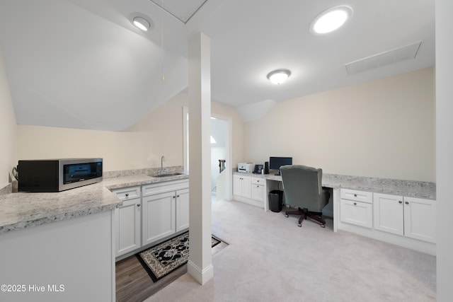 carpeted office with lofted ceiling, built in desk, and sink