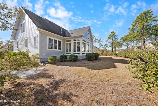 view of side of property featuring roof with shingles and a sunroom