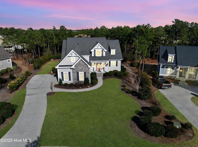 traditional-style house with concrete driveway, stone siding, a chimney, and a front yard