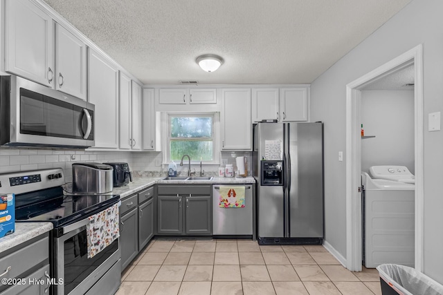 kitchen featuring appliances with stainless steel finishes, gray cabinetry, sink, separate washer and dryer, and white cabinets