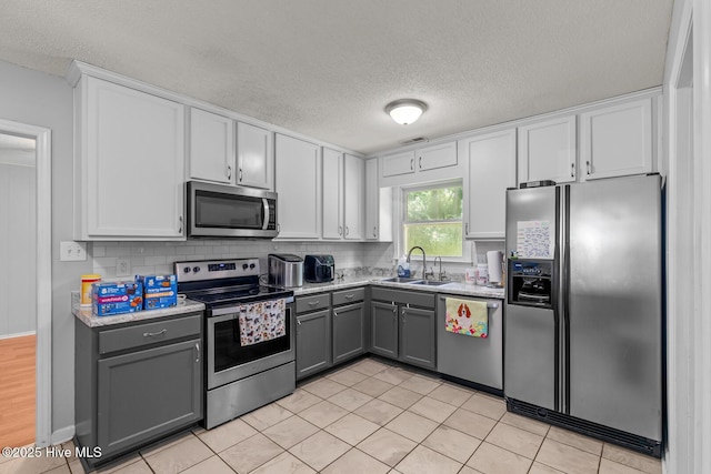 kitchen featuring gray cabinetry, a textured ceiling, stainless steel appliances, sink, and light tile patterned floors