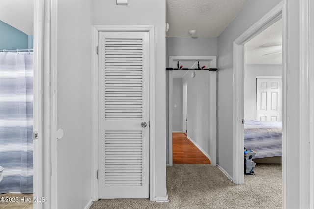 hallway featuring light carpet and a textured ceiling