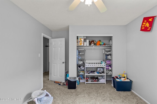 playroom featuring carpet flooring, ceiling fan, and a textured ceiling