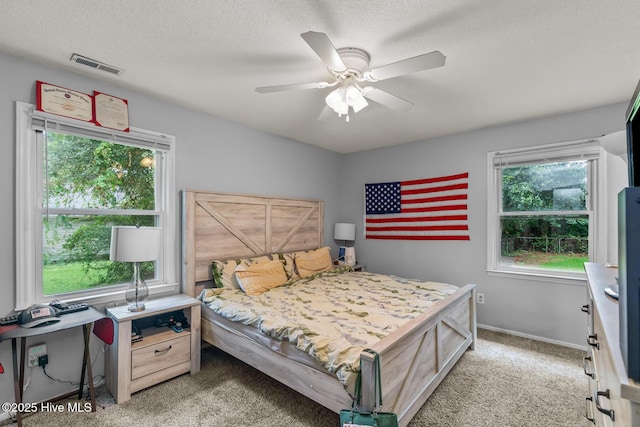 carpeted bedroom featuring ceiling fan and a textured ceiling