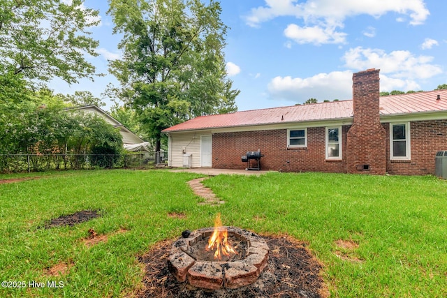 back of house with a patio area, a yard, and an outdoor fire pit