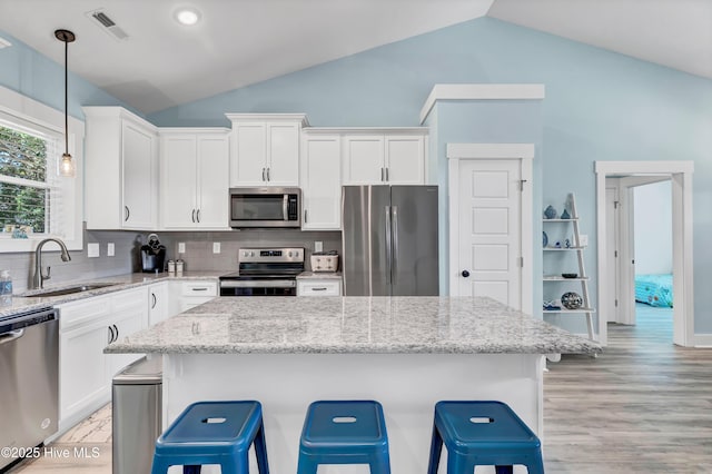 kitchen with sink, hanging light fixtures, decorative backsplash, white cabinetry, and stainless steel appliances