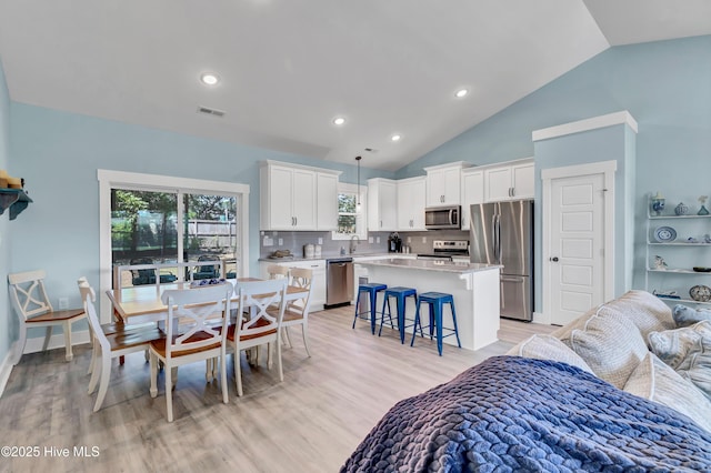 dining space with light hardwood / wood-style flooring, lofted ceiling, and sink