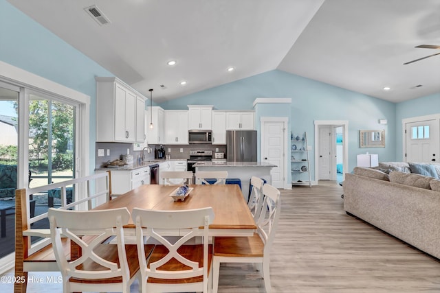 dining space with light hardwood / wood-style floors, vaulted ceiling, ceiling fan, and sink