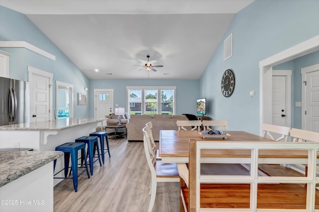 dining area with ceiling fan, lofted ceiling, and light hardwood / wood-style flooring