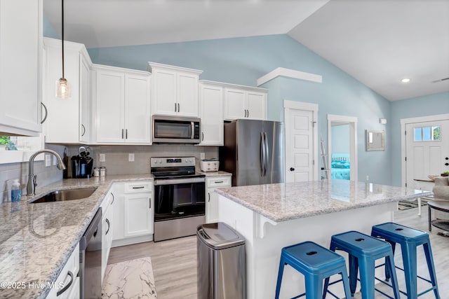 kitchen with appliances with stainless steel finishes, tasteful backsplash, sink, decorative light fixtures, and white cabinetry