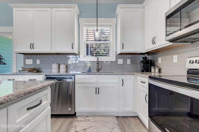 kitchen featuring white cabinets, pendant lighting, stainless steel appliances, and sink