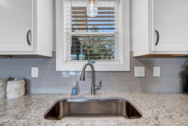 details with light stone countertops, white cabinets, and sink