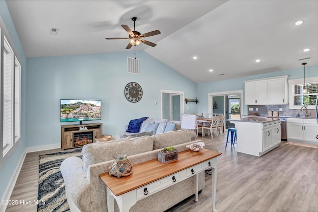 living room with a wealth of natural light, light hardwood / wood-style floors, ceiling fan, and lofted ceiling