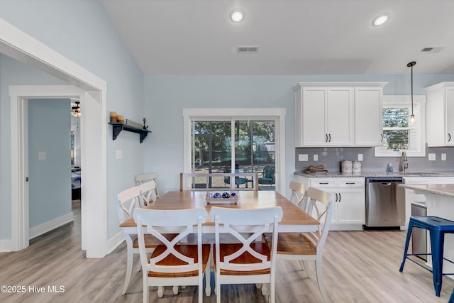 dining area with a wealth of natural light, sink, vaulted ceiling, and light wood-type flooring