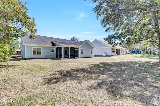 rear view of property featuring a lawn and a sunroom