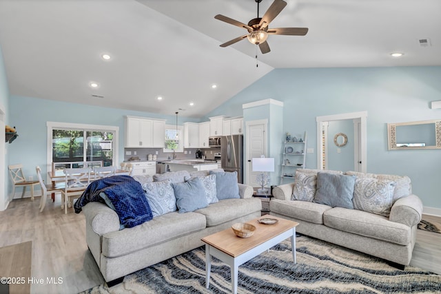 living room featuring ceiling fan, lofted ceiling, and light hardwood / wood-style flooring