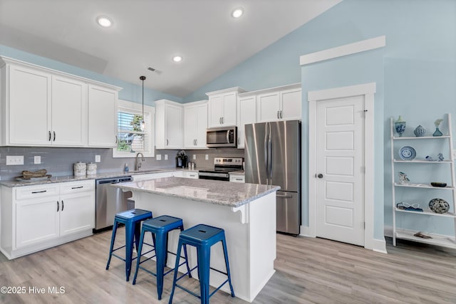 kitchen featuring white cabinets, a kitchen island, lofted ceiling, and appliances with stainless steel finishes